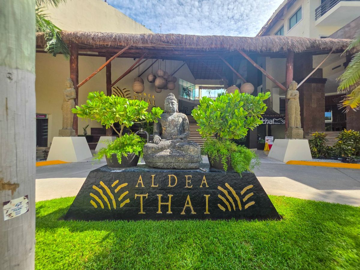 The entrance: a stone Buddha in front of the Aldea Thai sign