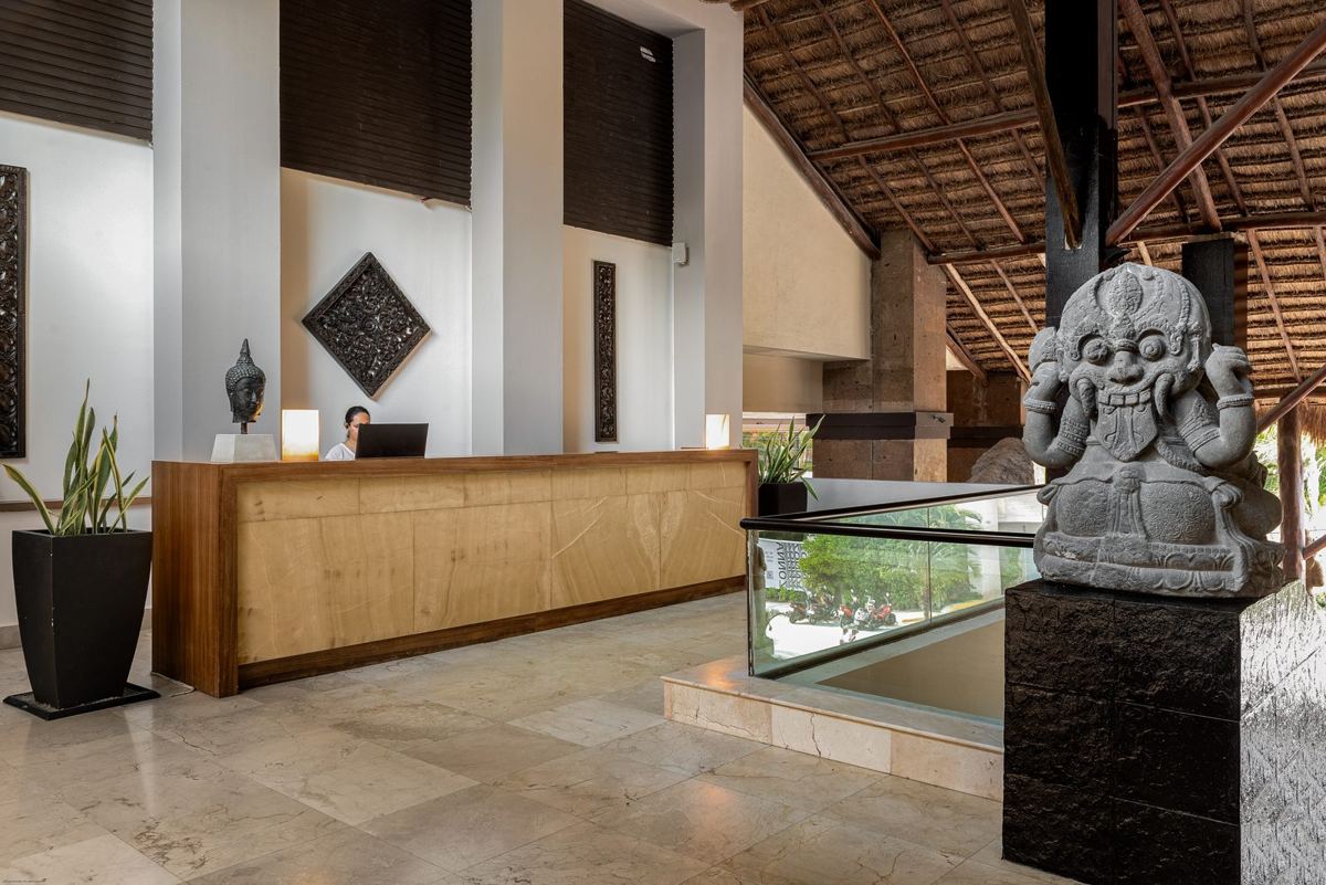 A squat crowned stone guardian with bulging eyes and fangs, beside the reception desk